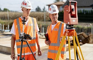 Two construction workers with helmets looking at a measuring device