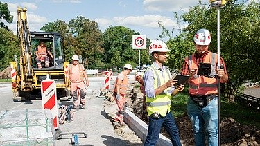 Zdjęcie: Kierownik Budowy wraz z pracownikami w odzieży ochronnej na placu budowy dem Strabag