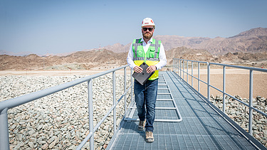 Karriere-Story Christoph Foto Mann mit Helm und Weste auf der Baustelle im Oman