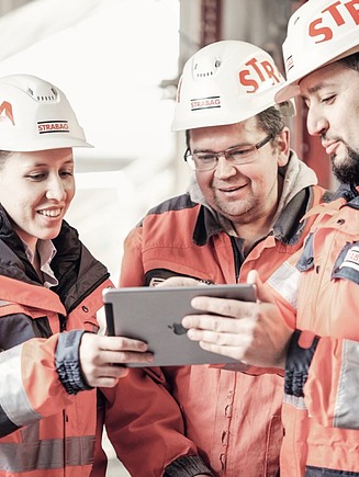 Foto Drie mensen met helm kijken naar een tablet