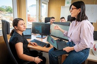 Kolegice sjede u uredu i jedna objašnjava drugoj