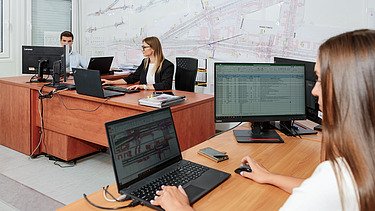 Zdjecie 3 osób z biurze budowy, patrzą na swoje monitory 