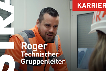 STRABAG Gruppenleiter im Baucontrainer bei einem Gespräch mit einer anderen Person welche einen weissen Helm mit STRABAG Logo trägt.