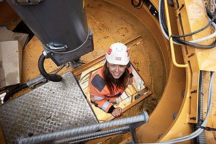 Foto von einer Bauleiterin, die gerade auf den Bau-Kran klettert