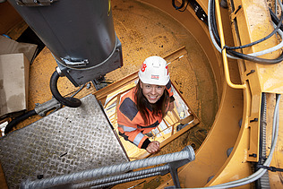 Foto von einer Bauleiterin, die gerade auf den Bau-Kran klettert