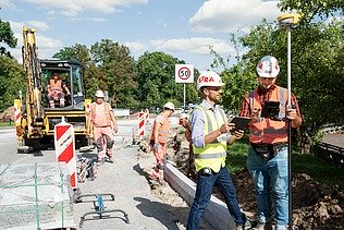 Zdjęcie: Kierownik Budowy wraz z pracownikami w odzieży ochronnej na placu budowy dem Strabag