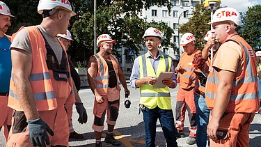Zdjęcie: Robert wraz z pracownikami budowlanymi ustalają kolejne etapy pracy z wykorzystaniem iPada. 