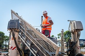 Mladi praktikant na gradilištu gleda u kameru