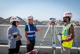 Drei Kolleg:innen besprechen sich zusammen auf der Baustelle im Oman