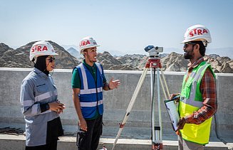 Drei Kolleg:innen besprechen sich zusammen auf der Baustelle im Oman