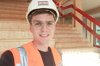 Selfie of young man with construction helmet, in the background you can see stairs made of wood