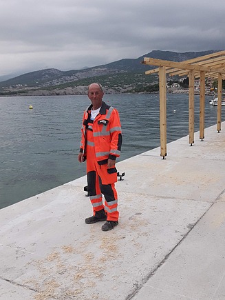 Bernard stoji pored mora na rivi u zaštitnom odijelu