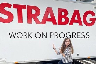 Vanessa stands in front of a STRABAG logo