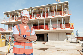 Photo Man with helmet stands infront of construction 
