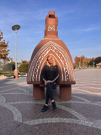 Tania na putovanju pozira ispred skulpture