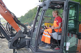 Praktikantin Leoni sitzt im Bagger und bedient ihn