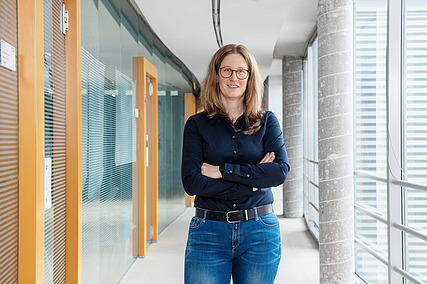 Frau steht mit verschränkten Armen in einem Flur