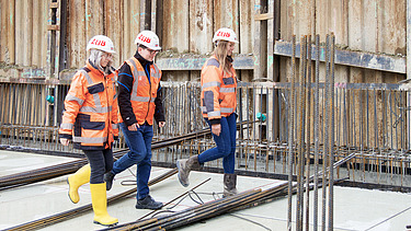 Foto von drei ZÜBLIN-Kolleg:innen, die über die Baustelle laufen
