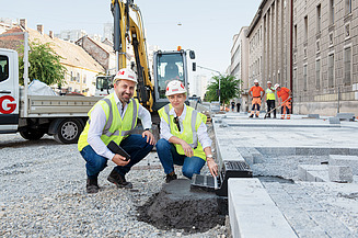 Kolege na gradilištu proveravaju put i gledaju u kameru