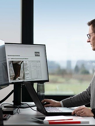 Bild von einem Mitarbeiter vor seinen Bildschirmen am Arbeitsplatz