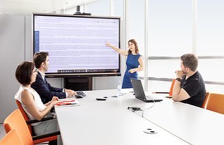 Melis presents something to her colleagues in front of a screen