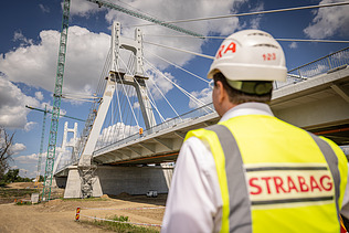 Un bărbat de pe șantier privește spre podul aflat în construcție.