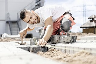 Foto: Marcel Voth beim Verlegen von Pflastersteinen