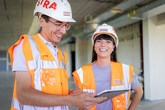 Foto von Frau, die am Bürotisch sitzt und in die Kamera lächelt