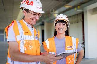Foto von Frau, die am Bürotisch sitzt und in die Kamera lächelt