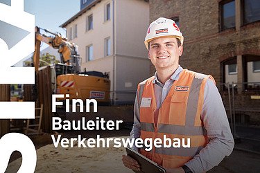 Mann mit Arbeitskleidung steht auf einer Baustelle