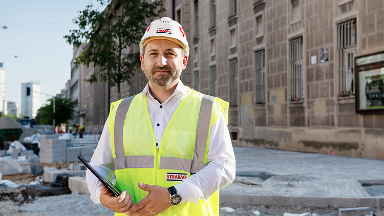 Kolega na gradilištu drži tablet u ruci i gleda u kameru