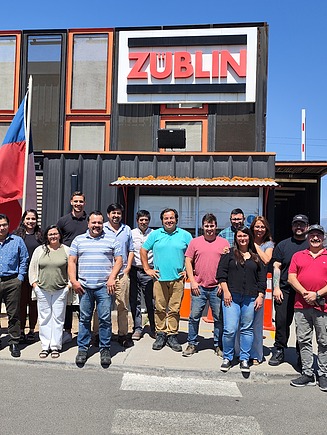 Employees stand in front of a building with the ZÜBLIN logo.
