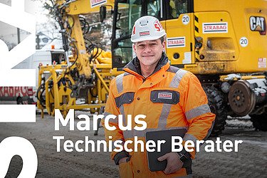 Mann mit Arbeitskleidung steht vor Baumaschinen auf einer Baustelle