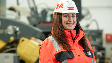 Fotografia kolegyne so stavebným strojom v pozadí