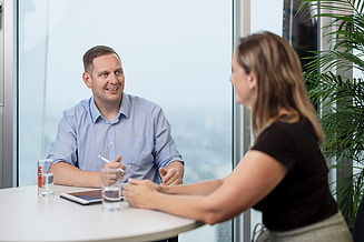 Employee interview 2 People in a meeting room seen through the glassfront of the room.