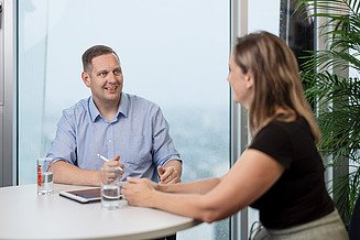 2 People in a meeting room seen through the glassfront of the room.