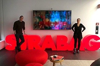 Two employees stand in front of a STRABAG lettering
