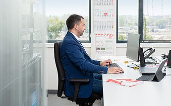 Kolega sedi za stolom u kancelariji i gleda u ekran