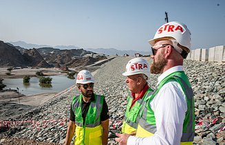 Colleagues stand together on a dam construction site in Oman