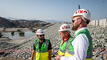 Colleagues stand together on the construction site in Oman