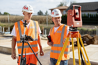 Two construction workers with helmets looking at a measuring device