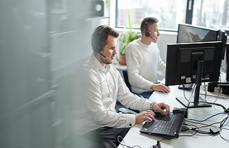 Zdjęcie dwóch mężczyzn podczas pracy w Service Desk, obierając połączenia i zgłoszenia od pracowników