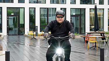 STRABAG employee on his company bike STRABAG employee on his company bike in front of the company building