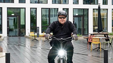 STRABAG employee on his company bike in front of the company building