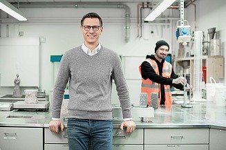 Bild eines Mitarbeiters am Arbeitsplatz im Labor mit Kollegen
