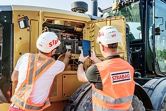 Kolege gledaju u motor stroja i slikaju s tabletom