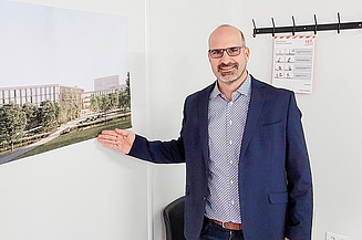 Christian Bittner, Oberbauleiter ZÜBLIN, verantwortet den Neubau des Landratsamts Esslingen Oberbauleiter Christian Bittner steht im Raum und deutet auf ein Projektbild des Landratsamt Esslingen
