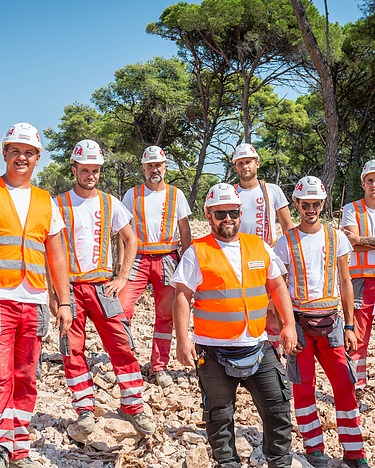 Kolege stoje na gradilištu i gledaju u kameru