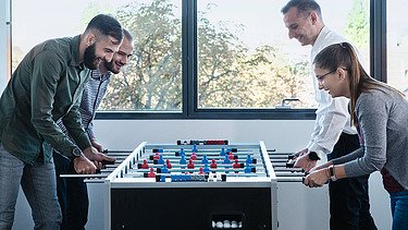 Fotografija četvoro kolega koji igraju stoni fudbal