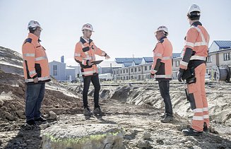 Photo Four men with helmet and jacket facing each other on construction site